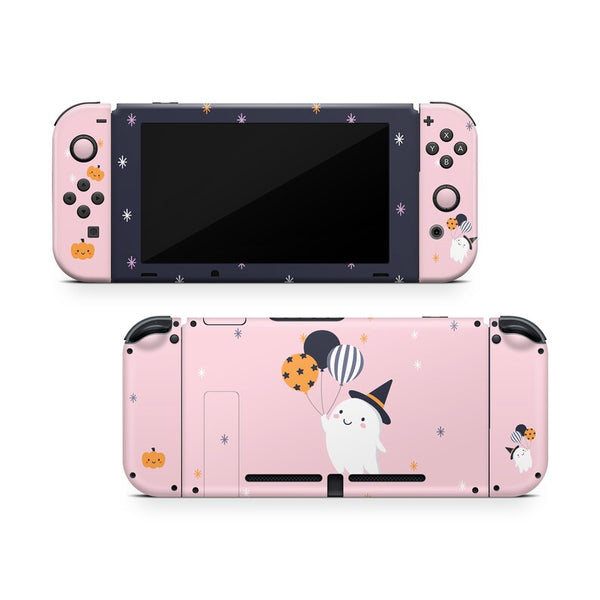 a pink Nintendo Switch console with a black and white design, decorated with Halloween-themed elements such as a ghost, pumpkins, and balloons.