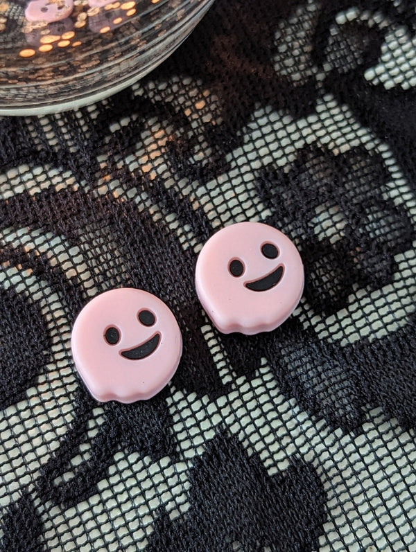 two pink smiley face buttons placed on a black and white lace background.