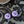 Load image into Gallery viewer, two purple smiley face-shaped objects placed on a black and white lace surface.
