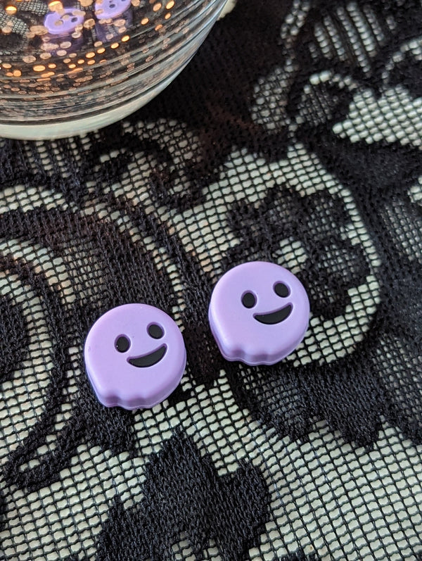 two purple smiley face-shaped objects placed on a black and white lace surface.