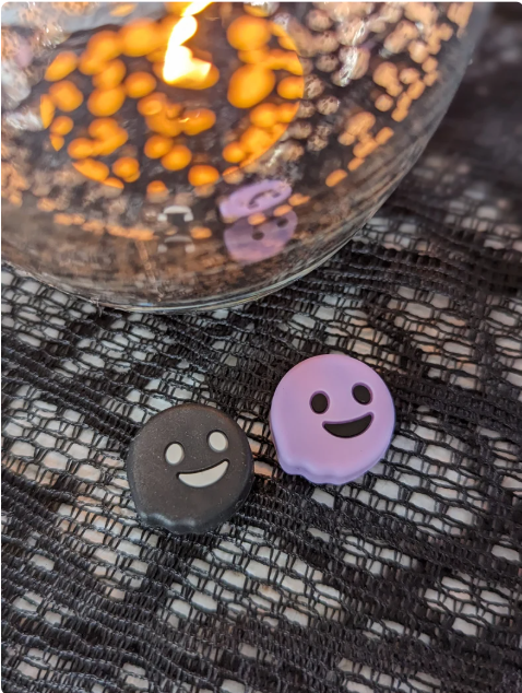 two small, round objects with faces on them, placed on a textured surface.
