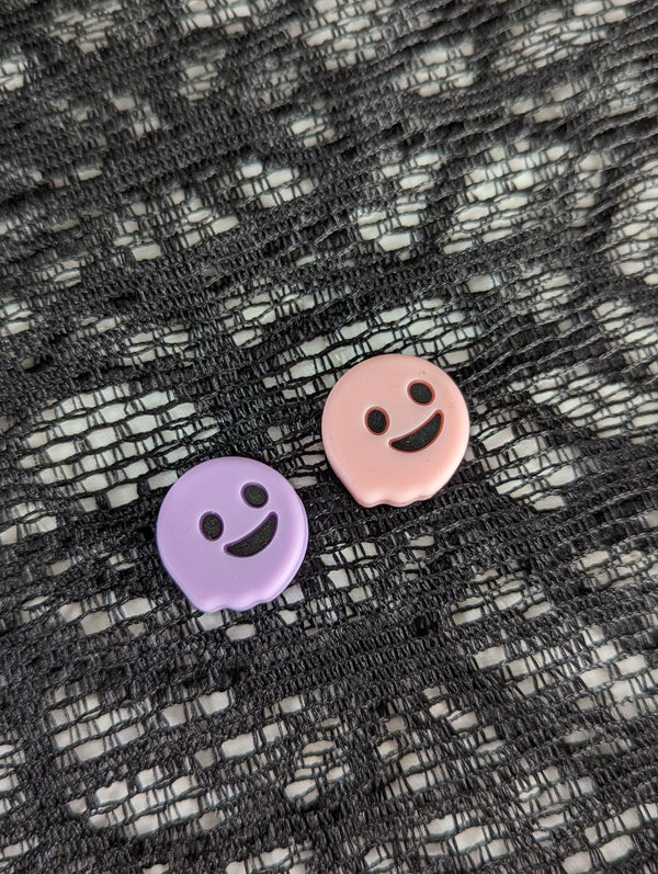 two round, smiling buttons with black eyes and mouths, placed on a black and white textured surface.
