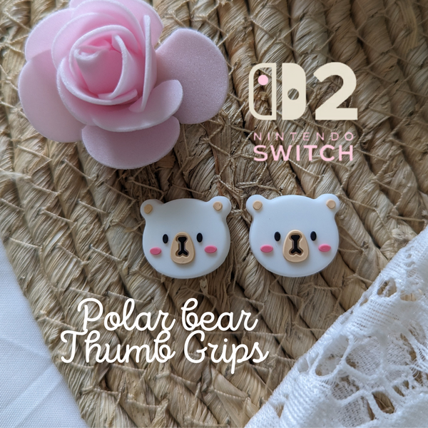 a pink rose, a Nintendo Switch, and two white polar bear-themed thumb grips on a woven surface.