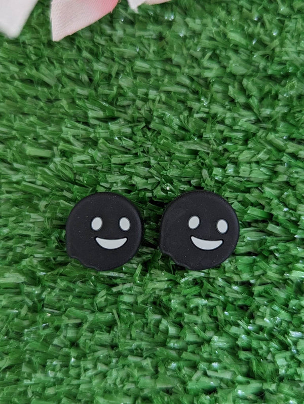 two black circles with white smiley faces on a green surface.