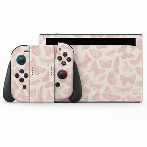 a Nintendo Wii console with a pink and white butterfly pattern skin. The console has two black and red buttons, and the two controllers are positioned next to each other.