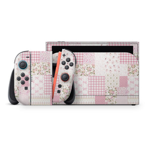 a Nintendo Switch console with a pink and white checkered pattern on its exterior. The console is accompanied by two controllers, one on each side, which are also covered in the same checkered pattern.